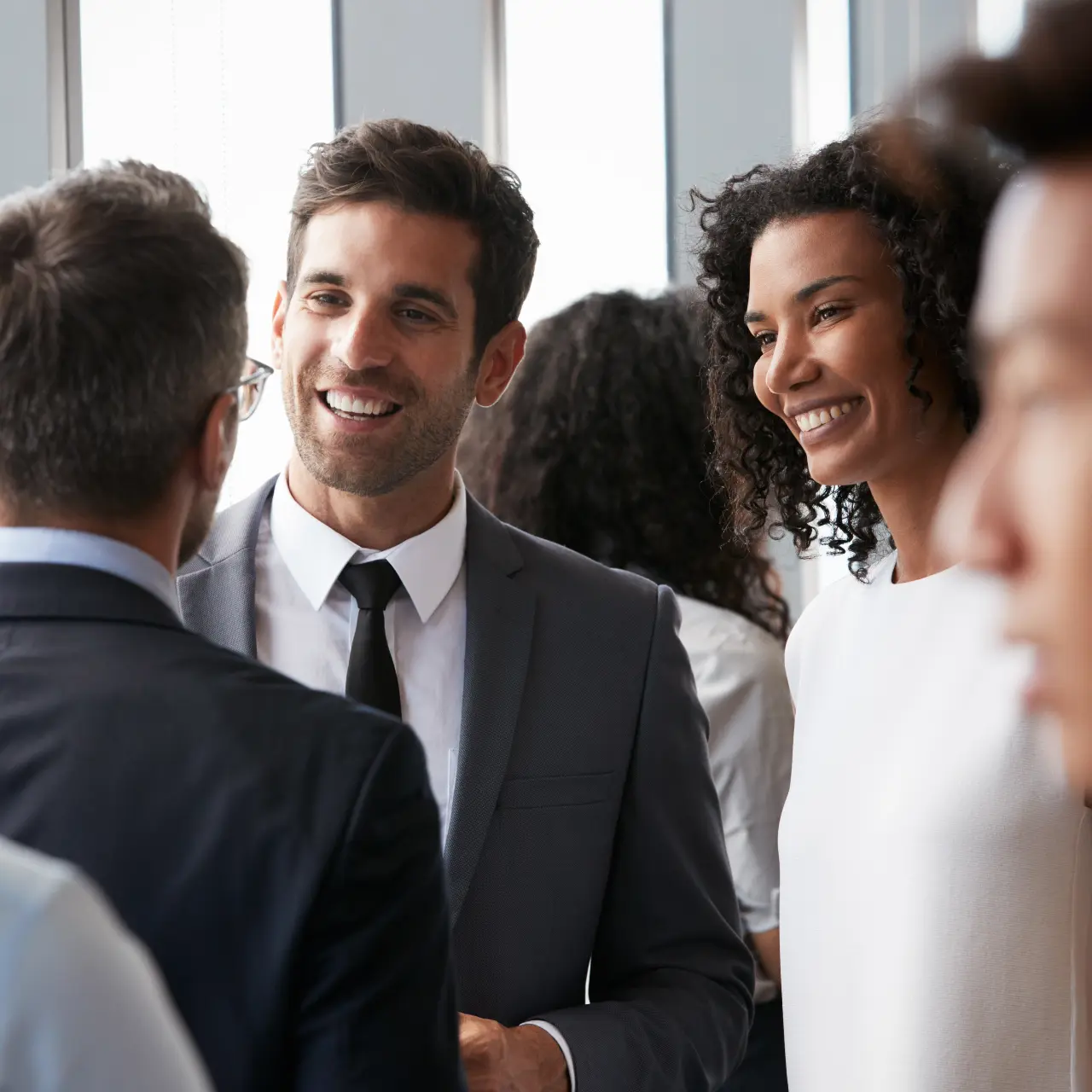 a woman and a man in suit talking to other people and networking